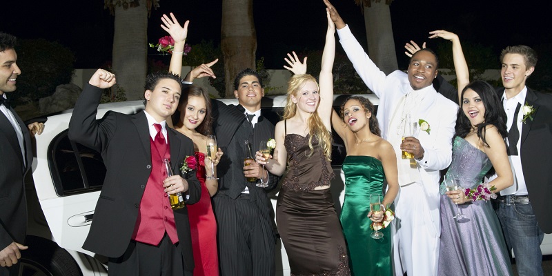 Teenage Boys and Girls Standing in Front of a Limousine Dressed for Their High School Prom