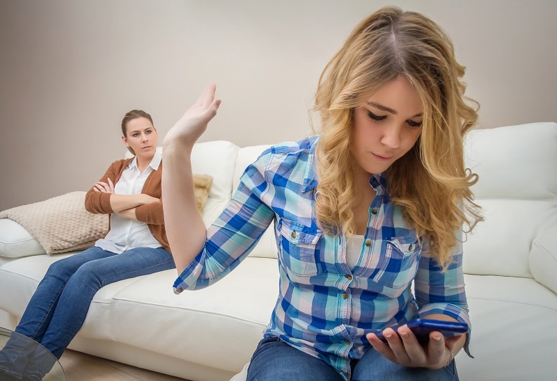 Daughter looking a phone and ignoring her mother